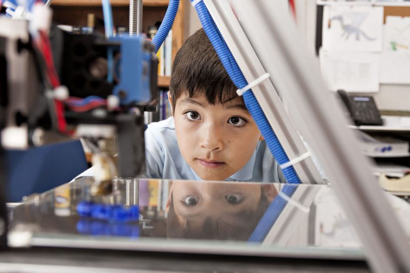Boy watches machine intently.