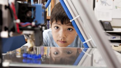 Boy watches machine intently.